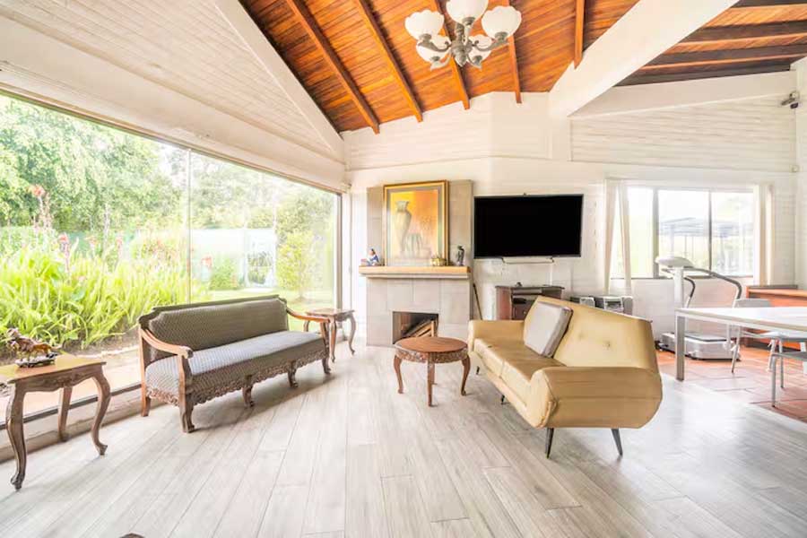 Sala interior luminosa con cubierta de madera y vista al jardín